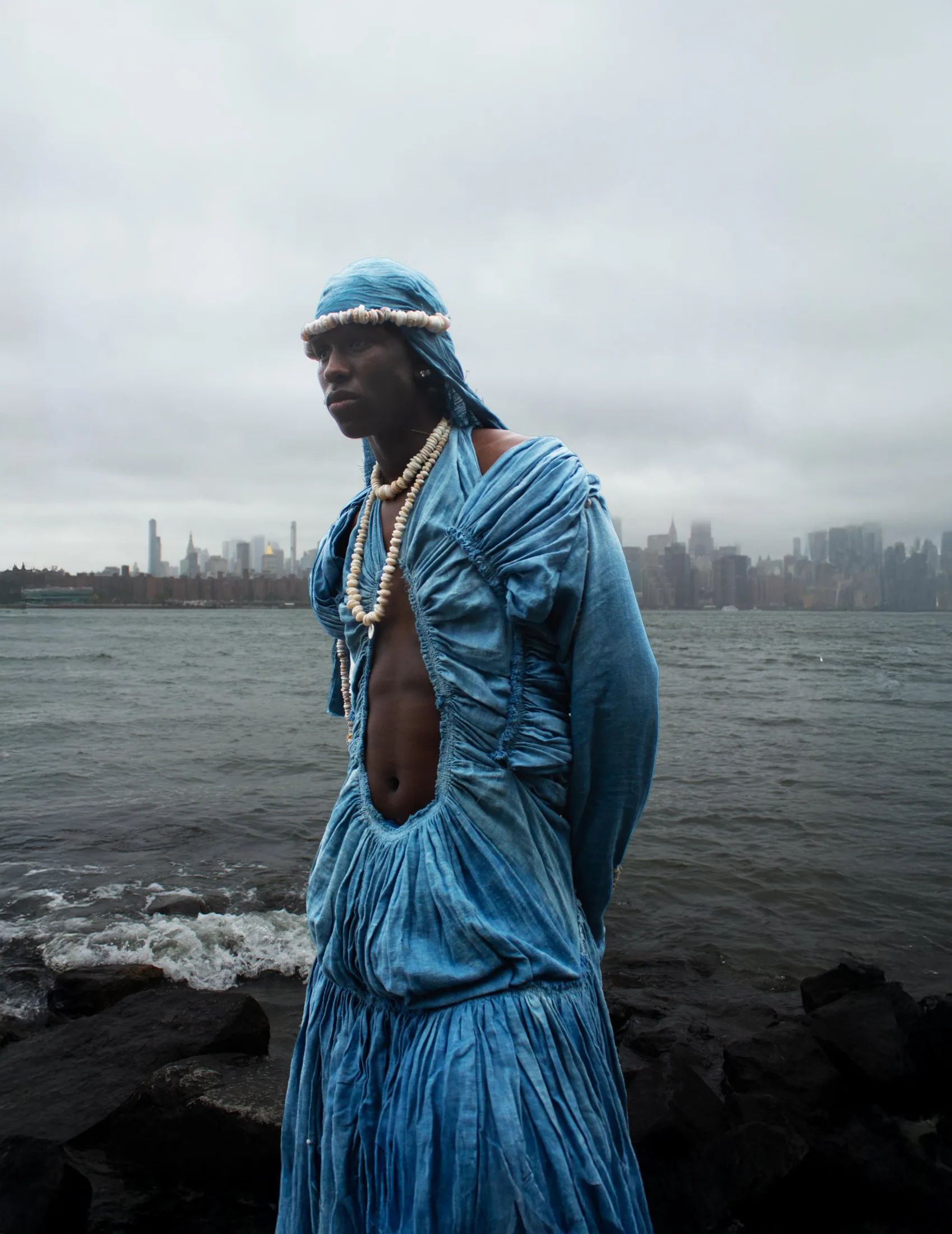 Mikael Pono's ruched blue gown with shell necklaces on the East River shore