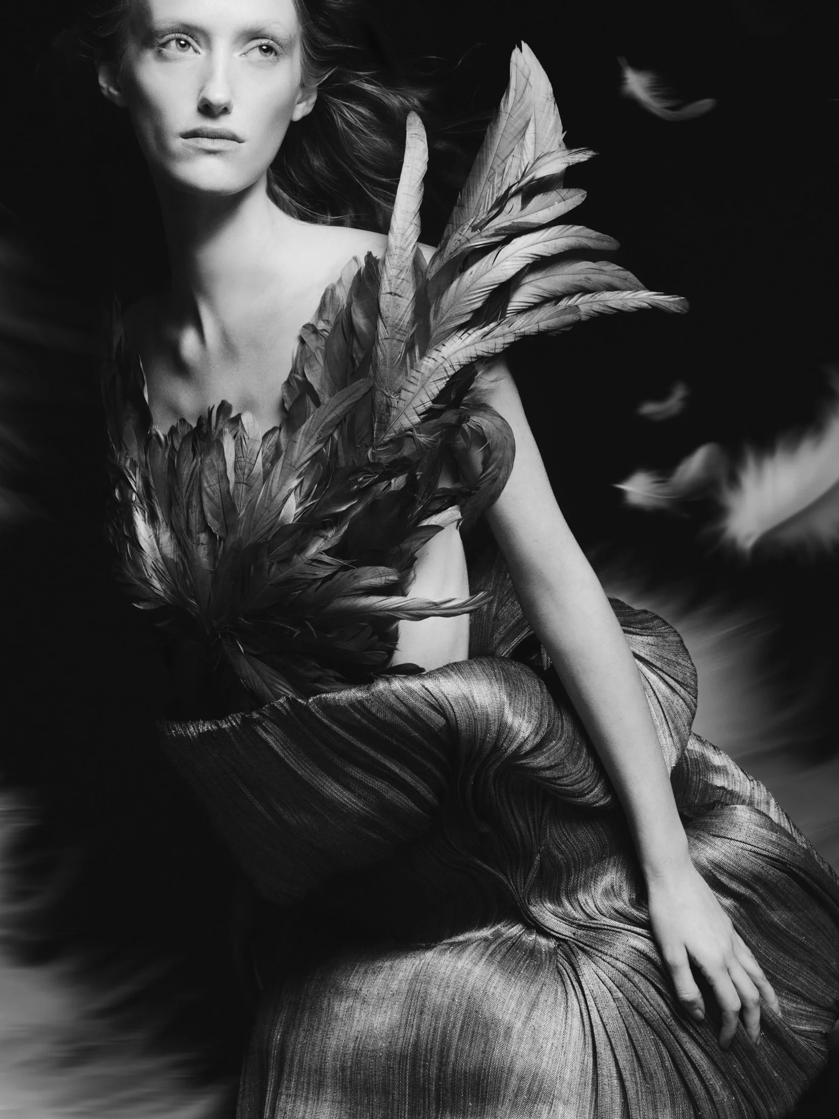 Faith in a feathered bodice and pleated metallic skirt, in black and white