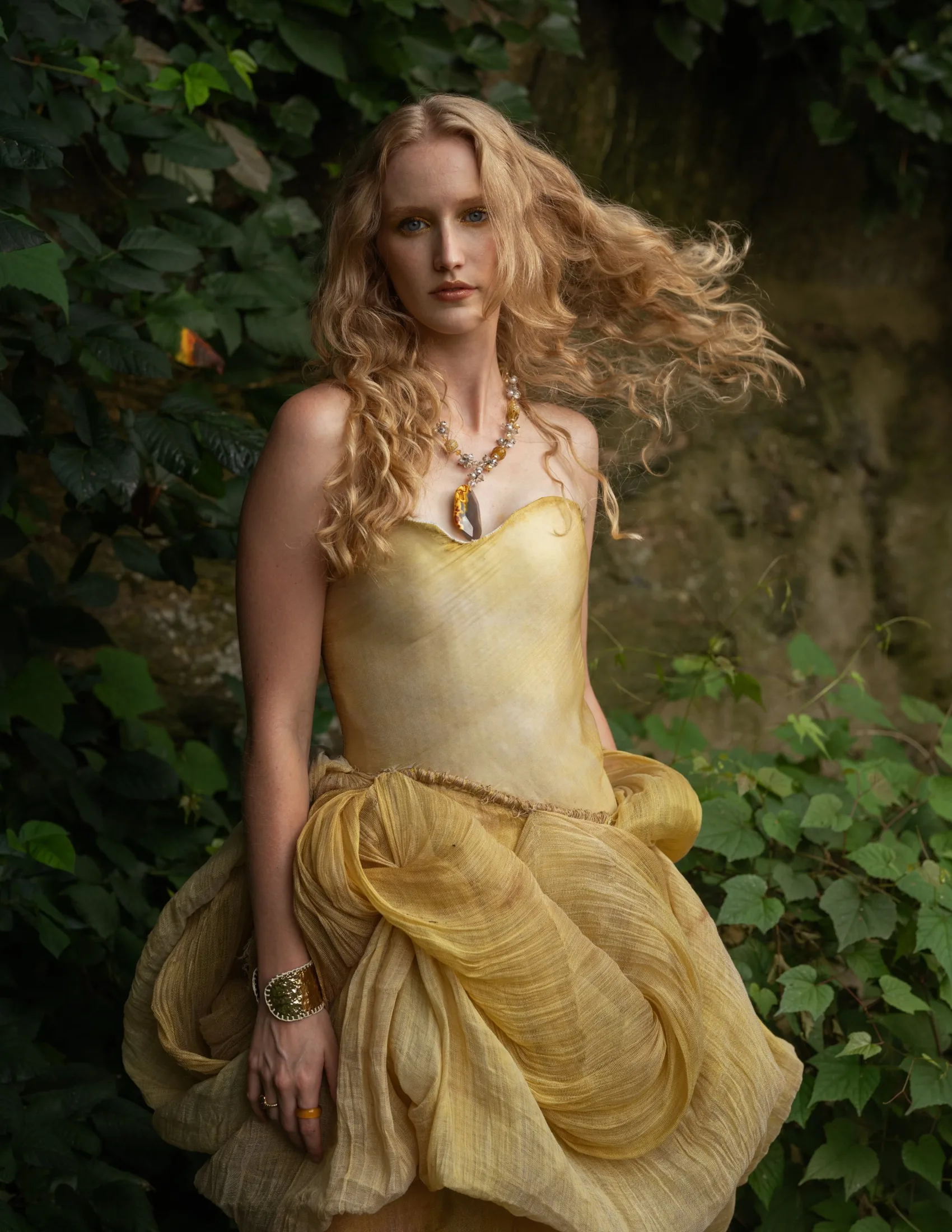 Haley Hyde in a hand-dyed yellow corseted gown among ivy