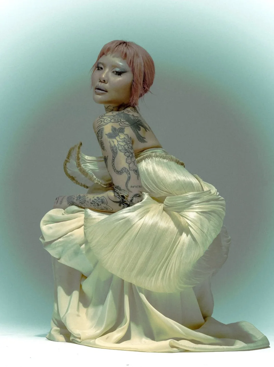 Mei kneeling in a pleated cream gown